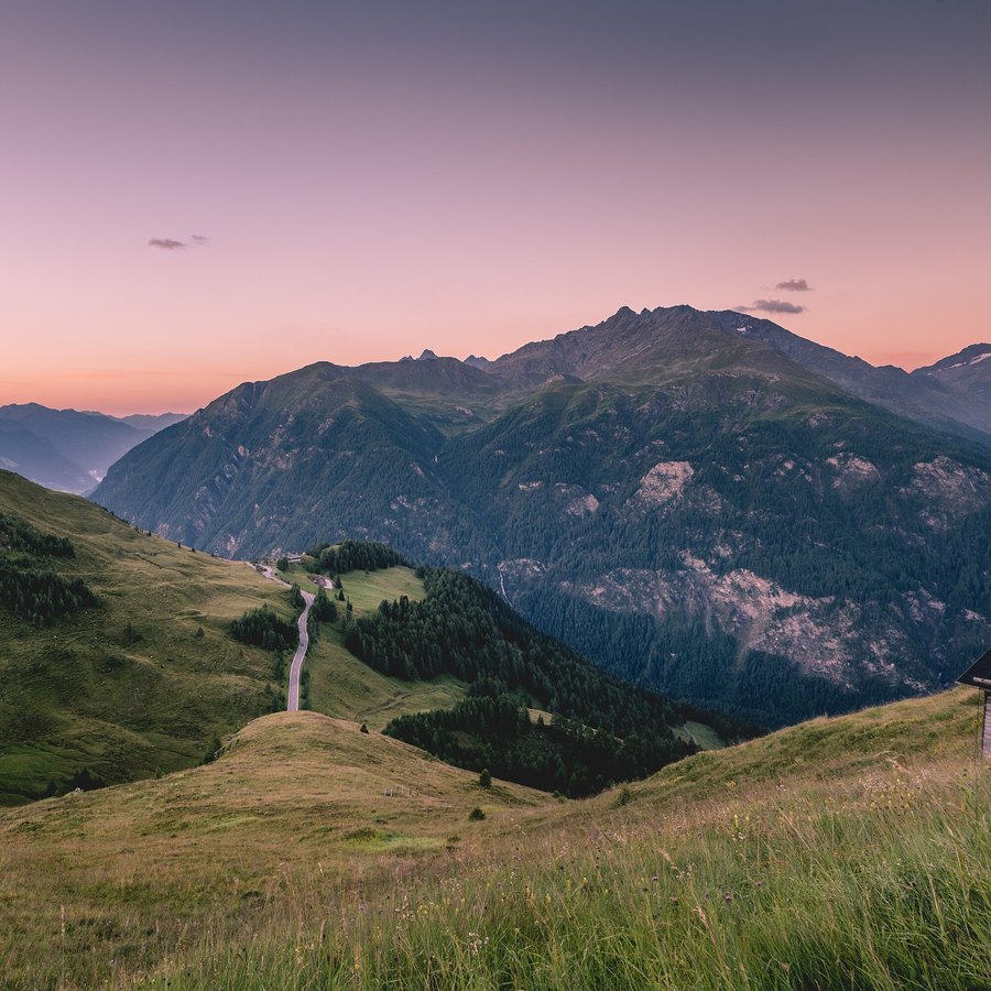 Grossglockner Hochalpenstraße som slynger seg gjennom fjellsidene under en rosa solnedgangshimmel