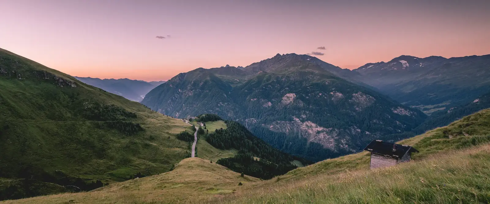 Grossglockner Hochalpenstraße som slynger seg gjennom fjellsidene under en rosa solnedgangshimmel